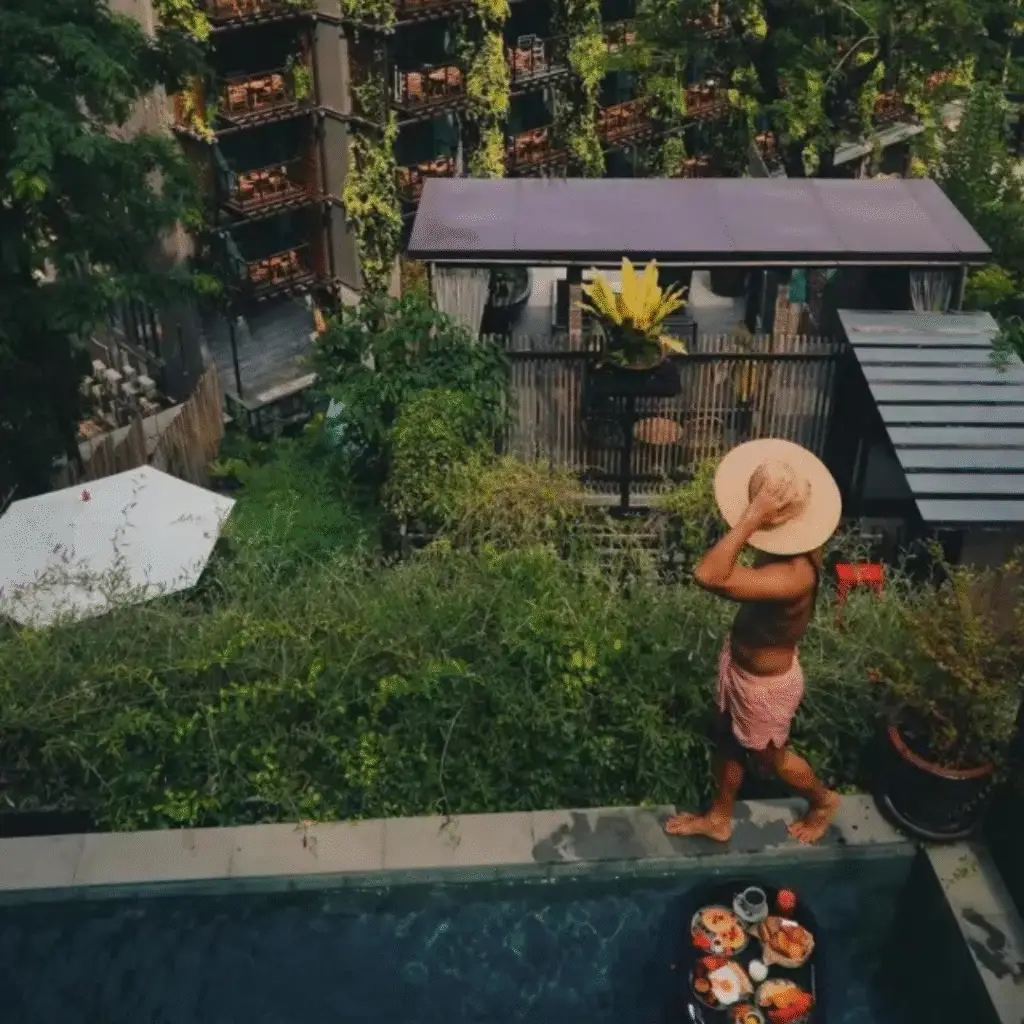 Man with straw hat walking near private plunge pool with floating breakfast