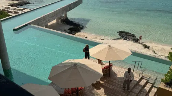 Expansive infinity pool at La Casa de la Playa with sun loungers and oceanfront views, blending seamlessly into the turquoise sea.