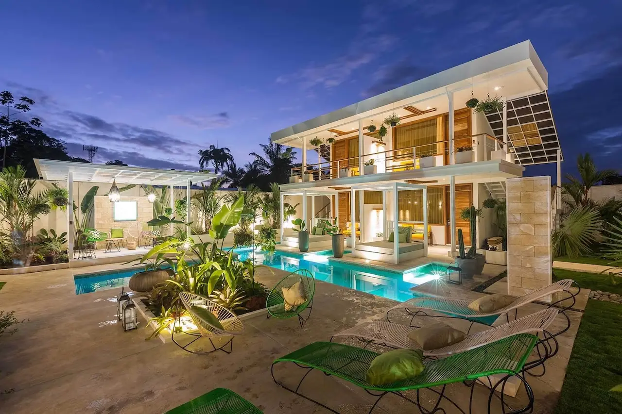 Twilight view of Umami Hotel Garden Spa with illuminated pool, lounge chairs, and tropical landscaping.