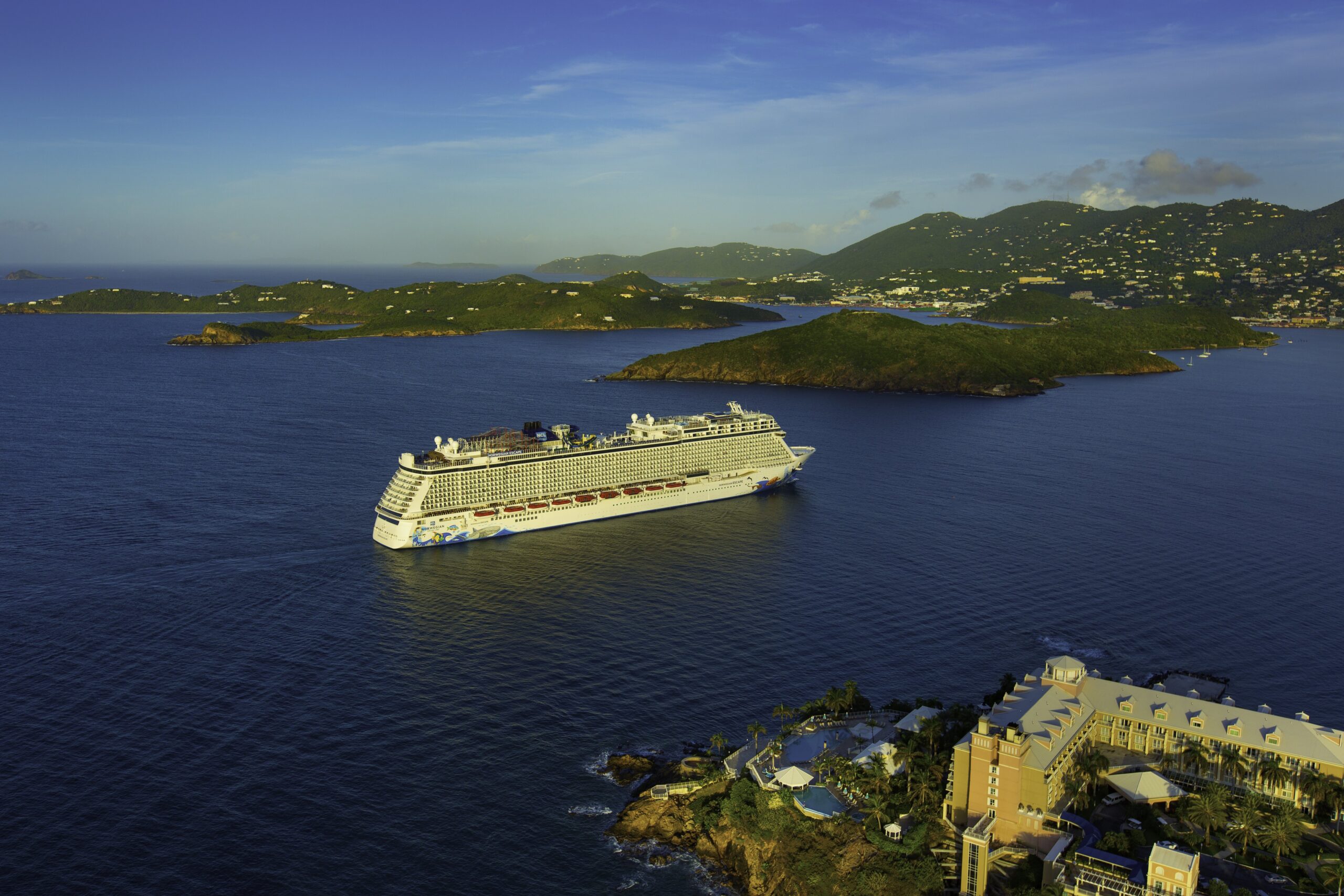 Norwegian Cruise Line ship sailing past lush Caribbean islands and turquoise waters