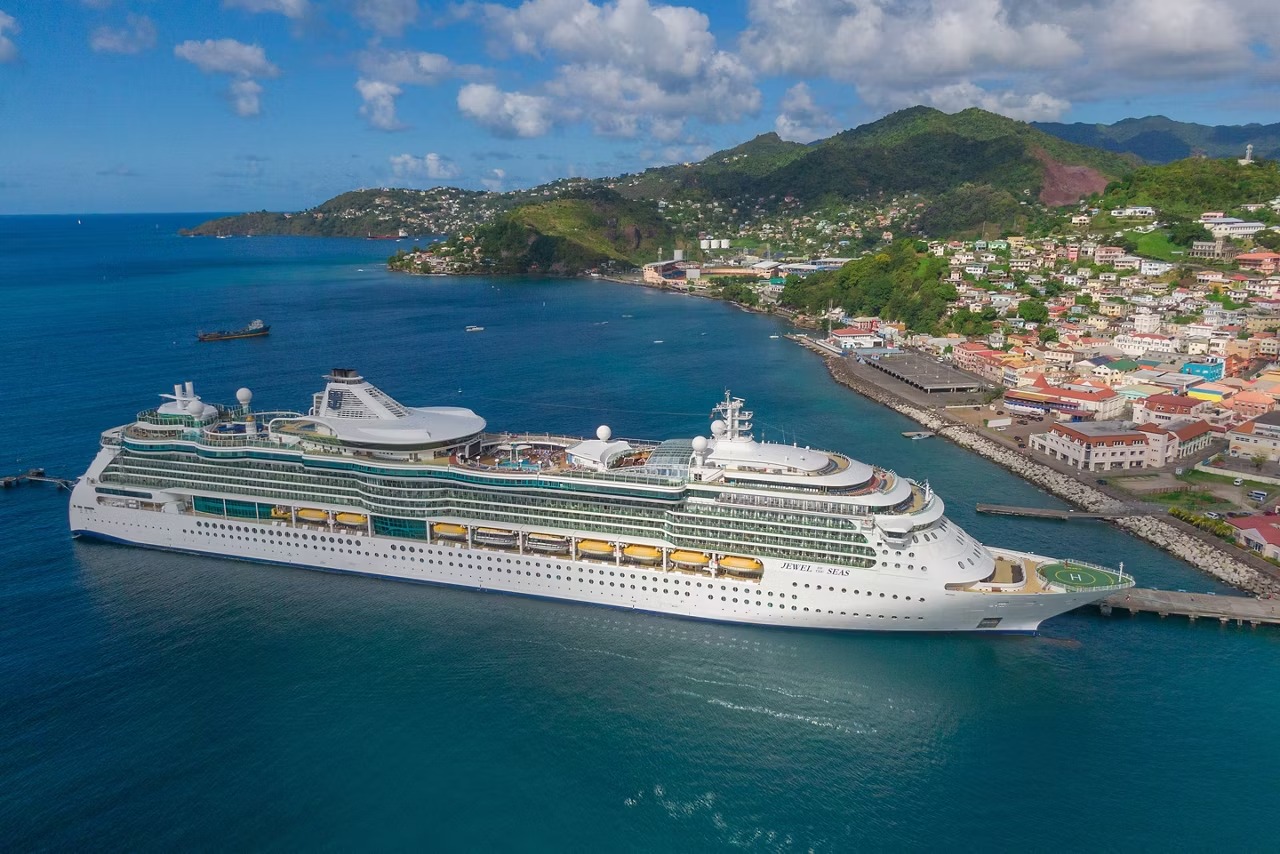 Norwegian Cruise Line ship docked at a Caribbean port with hillside town views