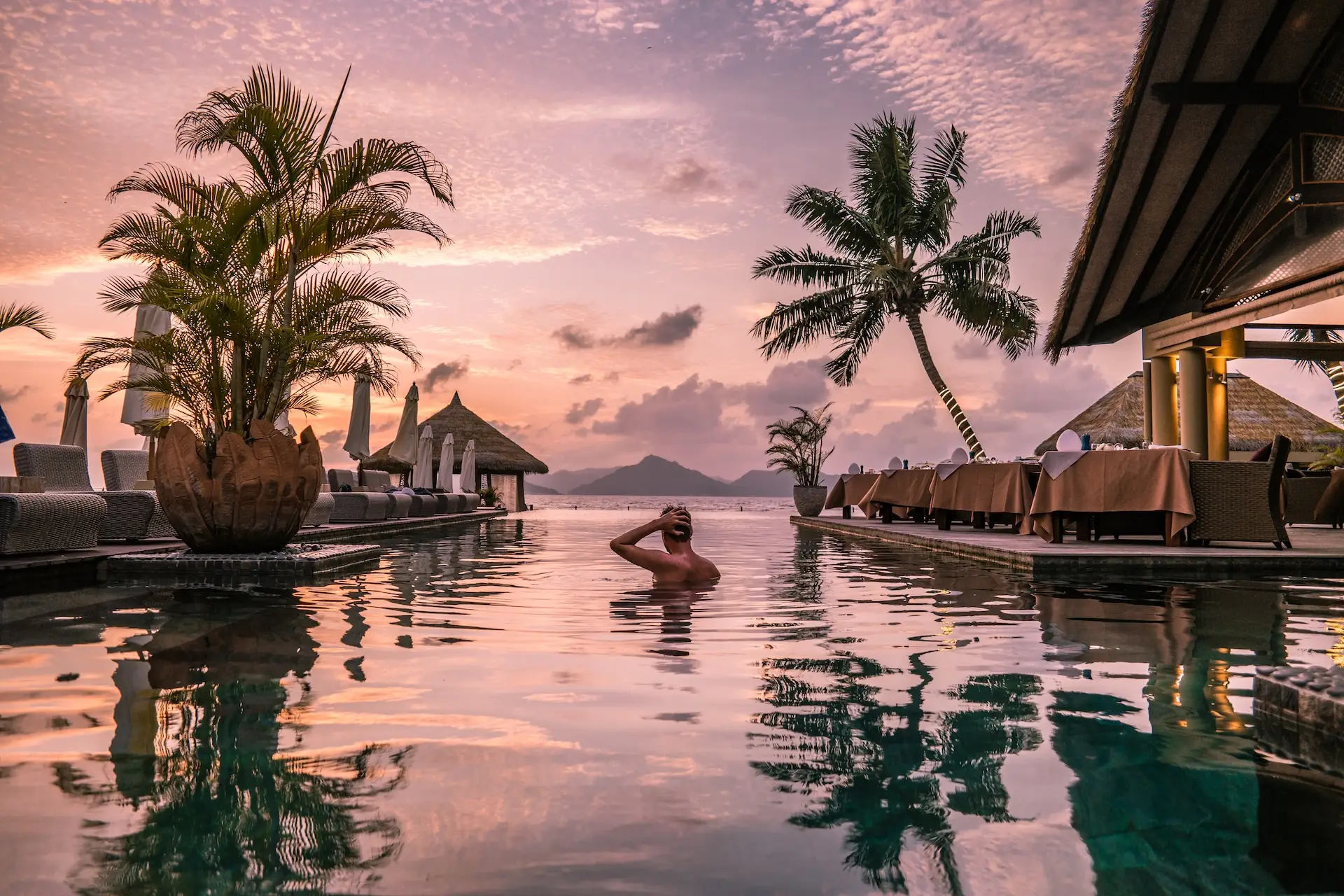 Person enjoying an infinity pool at sunset overlooking the ocean at an ultra luxury resort